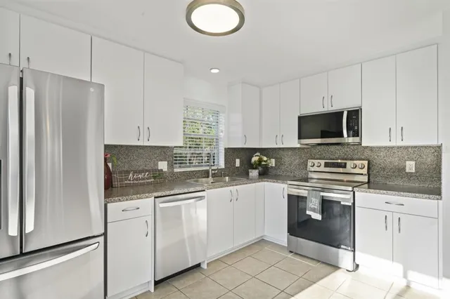 a kitchen with white cabinets stainless steel appliances and sink