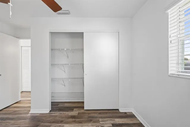 a view of an empty room with wooden floor and closet