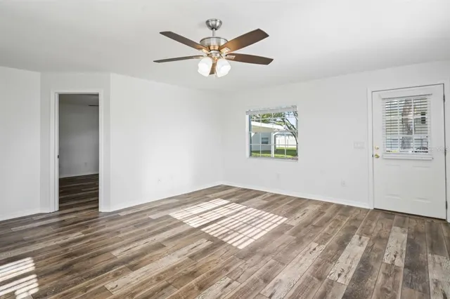 a view of empty room with wooden floor and ceiling fan