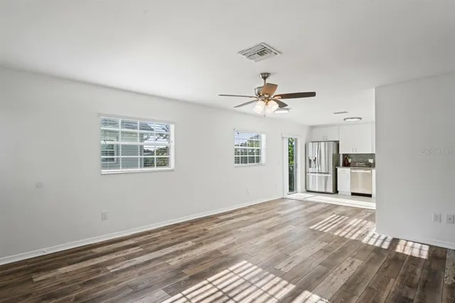 a view of empty room with wooden floor and ceiling fan
