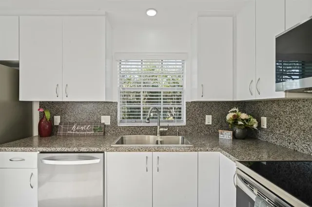 a kitchen with stainless steel appliances granite countertop white cabinets and a counter top space