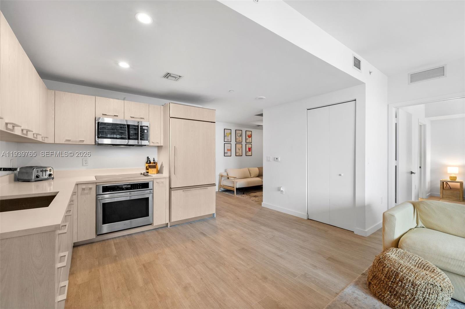 45 Southwest 9th Street, Unit 3802 Miami, FL 33130 - Photo 13 of 49 a kitchen with granite countertop a stove top oven a sink dishwasher and a refrigerator with wooden floor