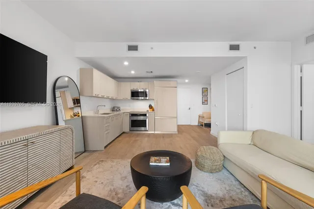 a living room with furniture a flat screen tv and white kitchen view