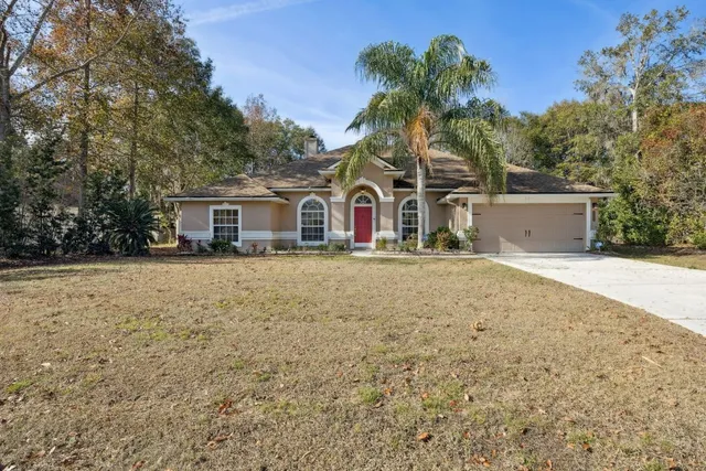 a front view of a house with large trees