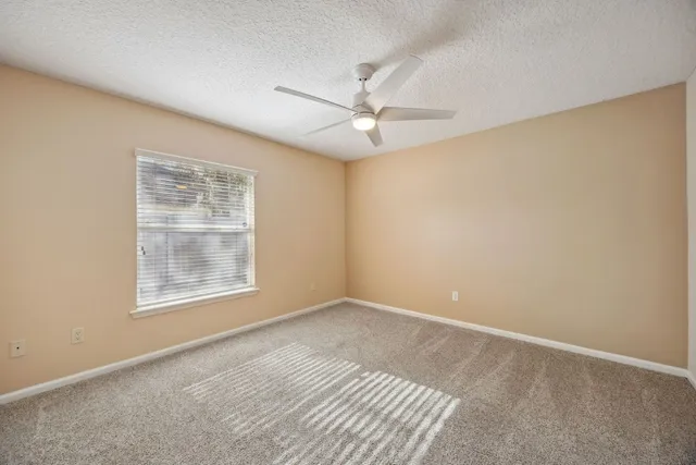 an empty room with windows and fan