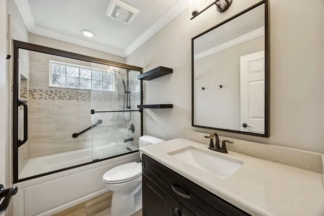 a bathroom with a granite countertop sink a toilet a mirror and shower