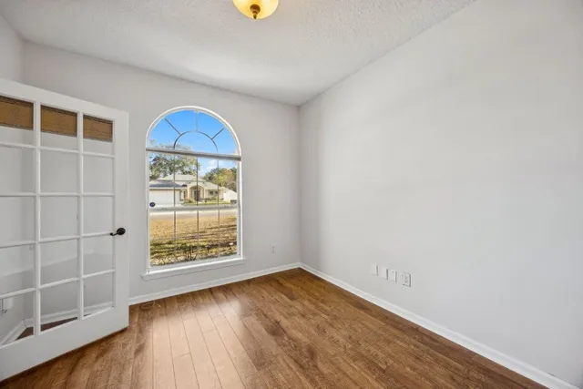 an empty room with wooden floor and windows