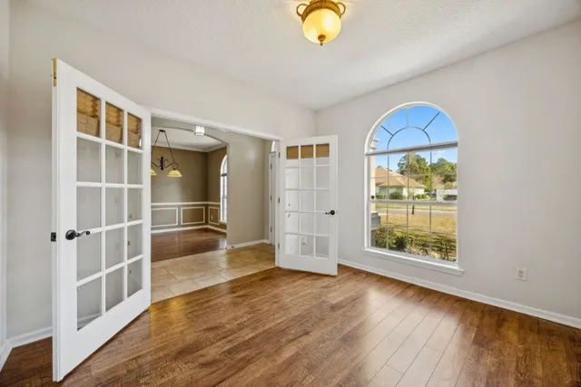 an empty room with wooden floor and windows