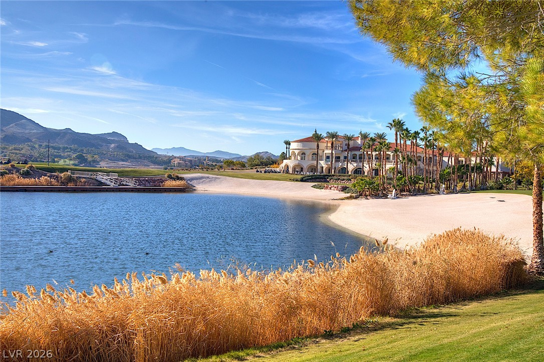 25 Falling Ridge Lane Henderson, NV 89011 - Photo 41 of 48 A picturesque golf course setting with serene waters and a grand clubhouse, framed by rolling hills.