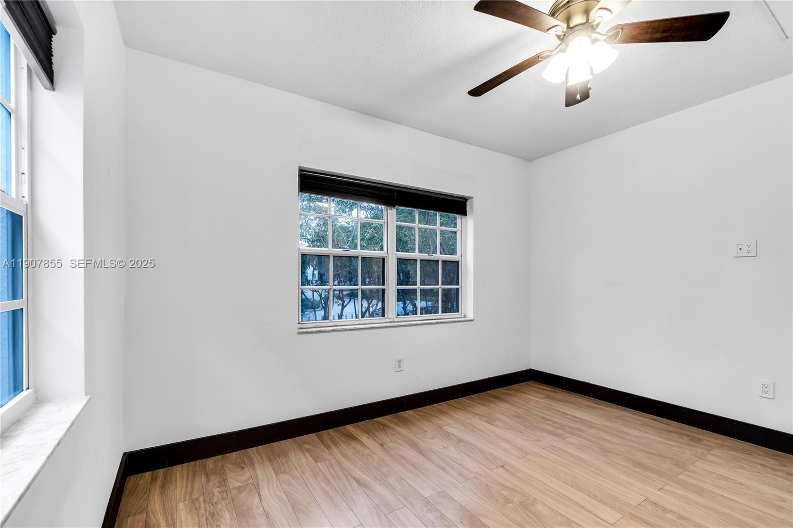 8335 Crespi Boulevard, Unit 4 Miami Beach, FL 33141 - Photo 12 of 25 an empty room with wooden floor fan and windows