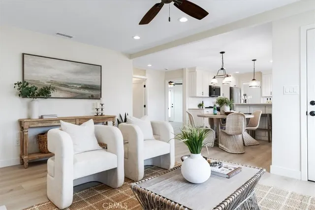 a living room with furniture potted plant and kitchen view