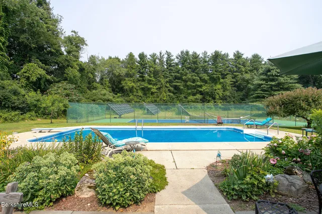 a view of a swimming pool with a yard and large trees