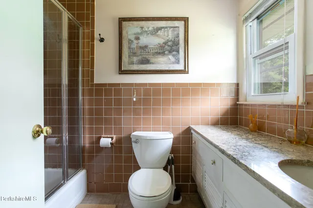 a bathroom with a granite countertop toilet a sink and a shower
