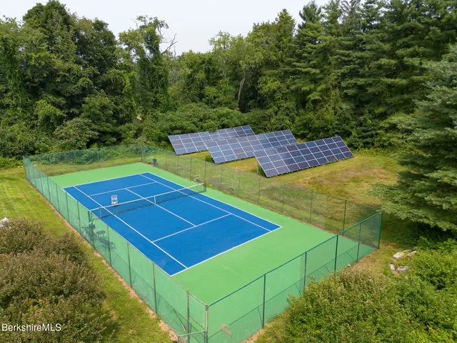 a view of a tennis ground with large trees