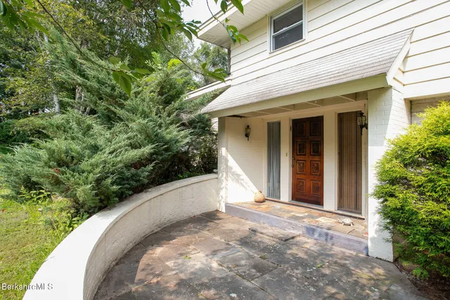 a view of a white house with a yard potted plants and a tree