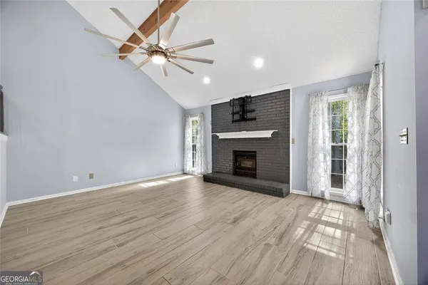 an empty room with wooden floor fireplace and windows