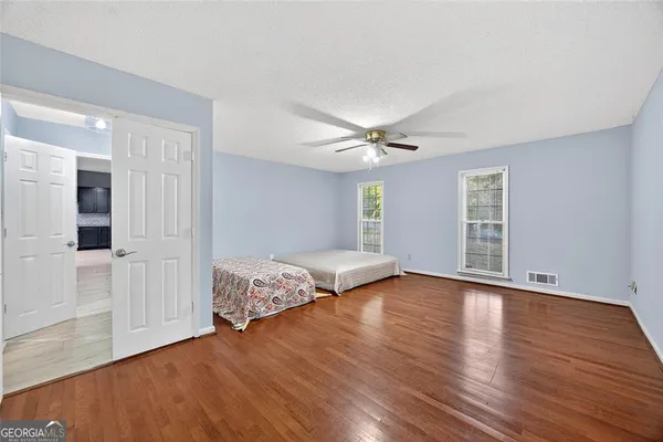 an empty room with wooden floor fan and windows
