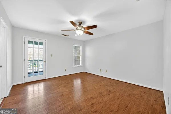 an empty room with wooden floor and windows