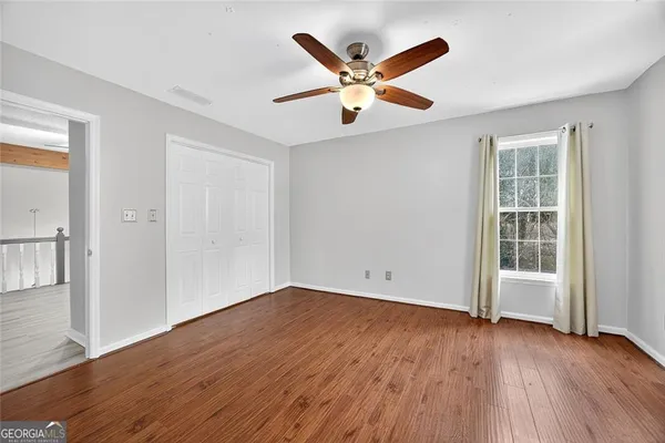 a view of an empty room with wooden floor and a window