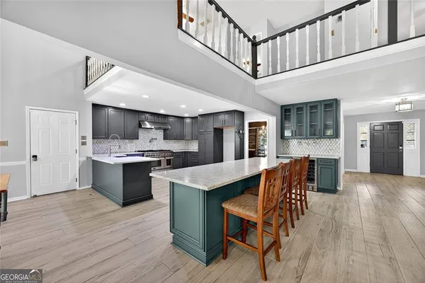 a kitchen with stainless steel appliances kitchen island granite countertop a table chairs in it and wooden floors