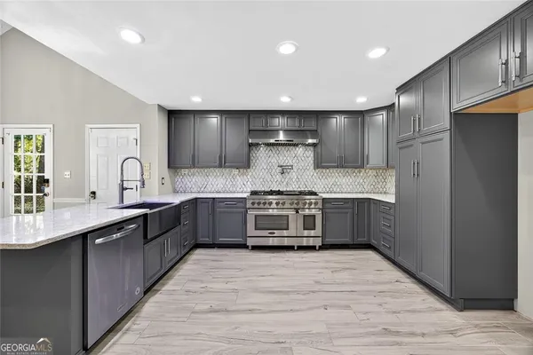 a large kitchen with stainless steel appliances kitchen island granite countertop a stove and a sink