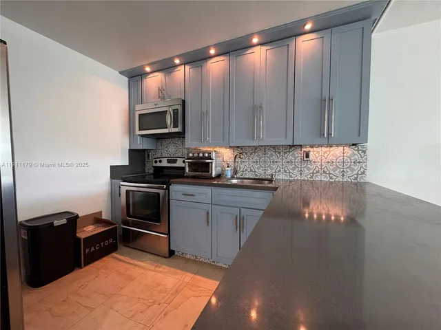 a kitchen with granite countertop a refrigerator stove and microwave