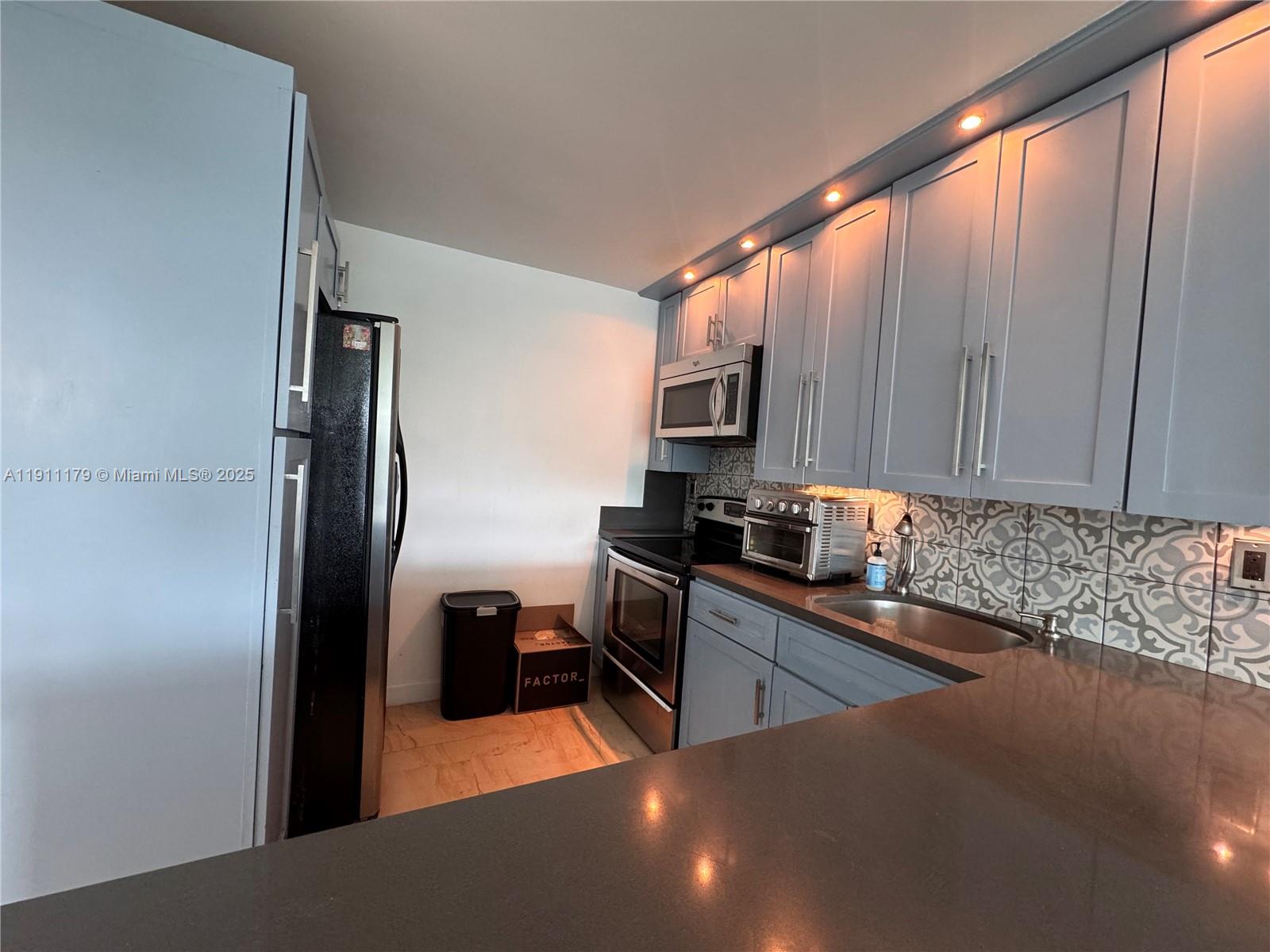 8233 Harding Avenue, Unit 403 Miami Beach, FL 33141 - Photo 5 of 11 a kitchen with stainless steel appliances a sink a stove and a refrigerator