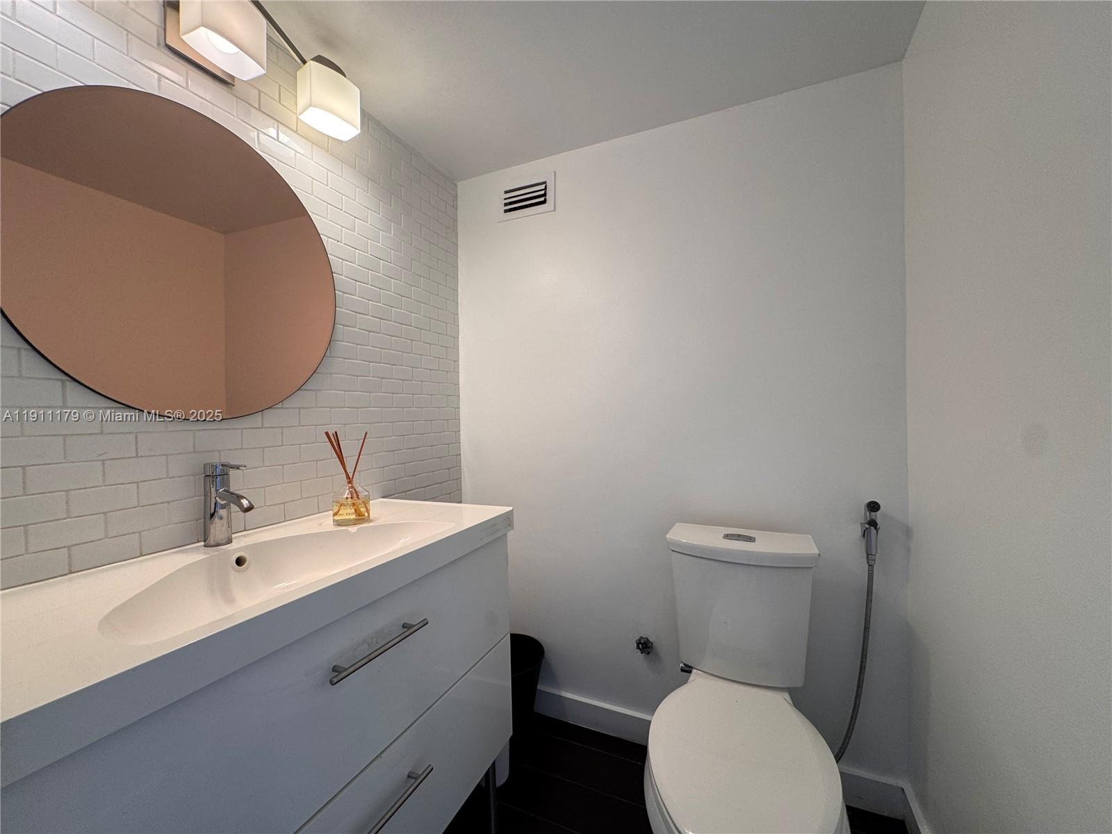 8233 Harding Avenue, Unit 403 Miami Beach, FL 33141 - Photo 10 of 11 a bathroom with a toilet sink and mirror