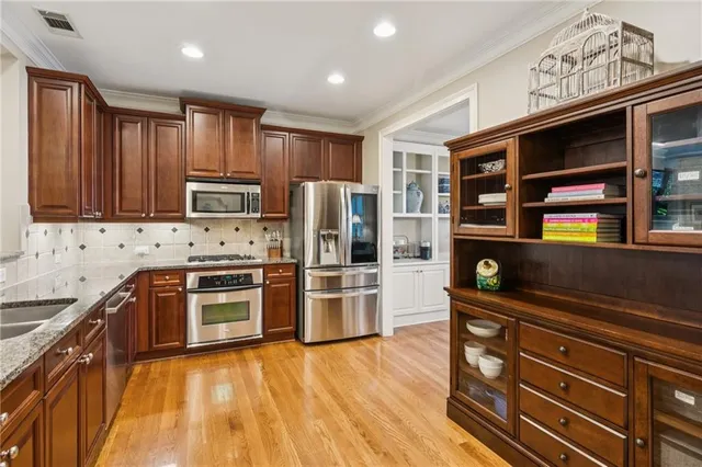 a kitchen with stainless steel appliances granite countertop wooden cabinets a sink and dishwasher with wooden floor