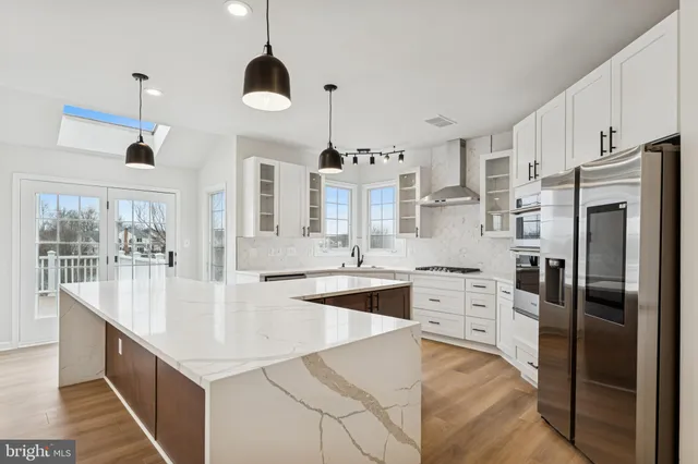 a large kitchen with kitchen island a large counter top stainless steel appliances and cabinets