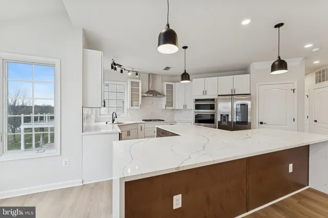 a large kitchen with kitchen island a stove a sink a center island and wooden floor