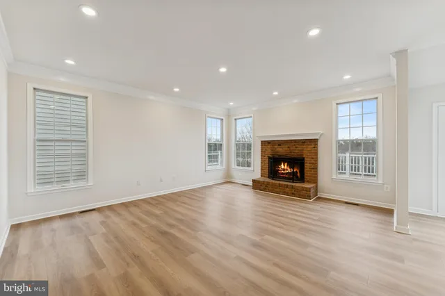 an empty room with wooden floor fireplace and windows