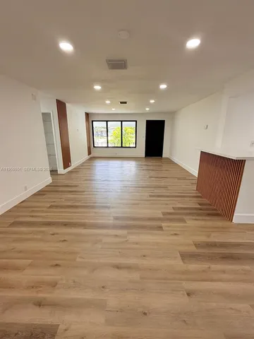 a view of empty room with window and wooden floor