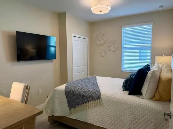 a bedroom with a bed a flat screen tv and guitar
