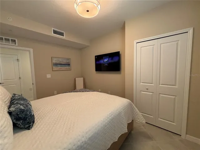 a bedroom with a bed and a flat tv screen on dresser