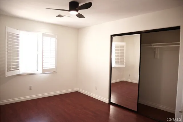 an empty room with wooden floor cabinet and windows