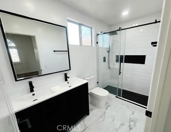 a bathroom with a sink a toilet a mirror and shower
