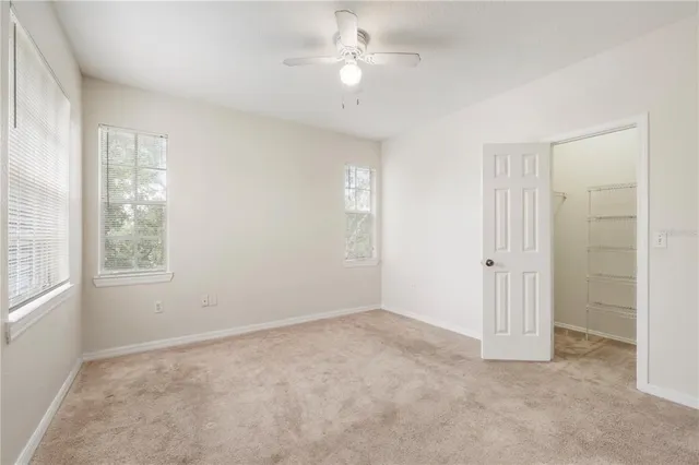 an empty room with windows and fan