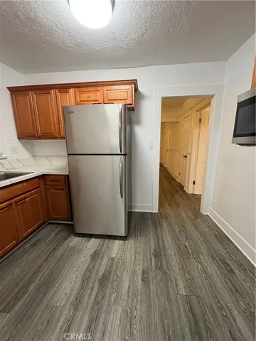 a view of a kitchen with wooden floor and a refrigerator