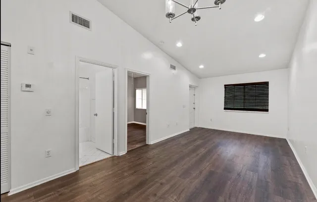 an empty room with wooden floor and a ceiling fan