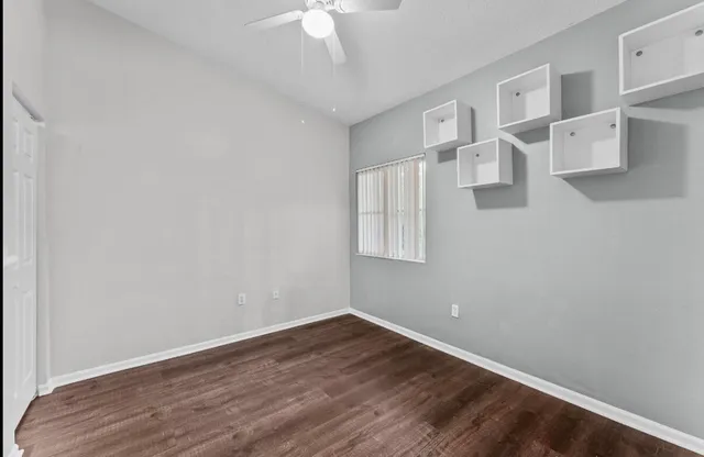 an empty room with windows and fan