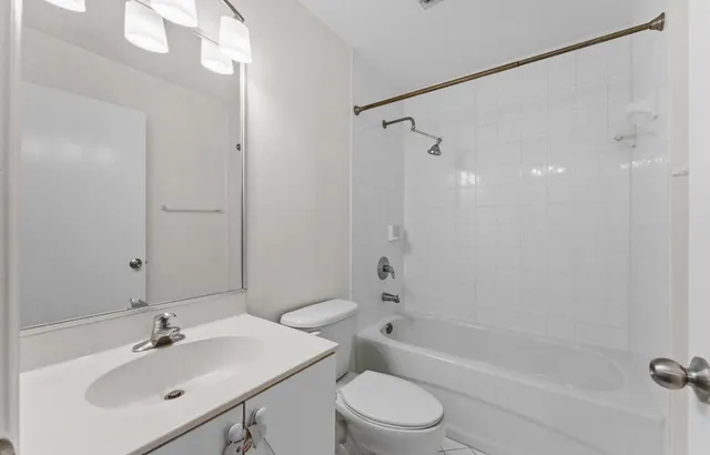 a bathroom with a bathtub shower sink vanity and toilet