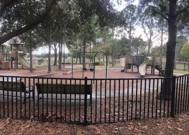 a view of a brick house next to a yard with large trees