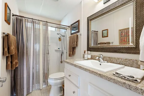a bathroom with a granite countertop sink toilet and shower