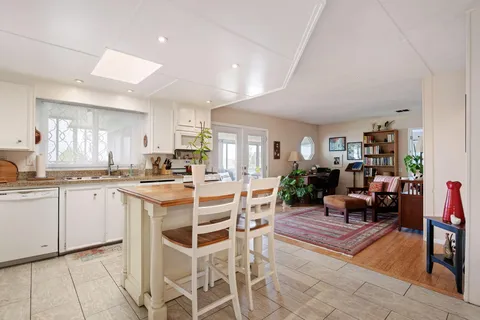 a kitchen with stainless steel appliances kitchen island granite countertop a table chairs and a living room view