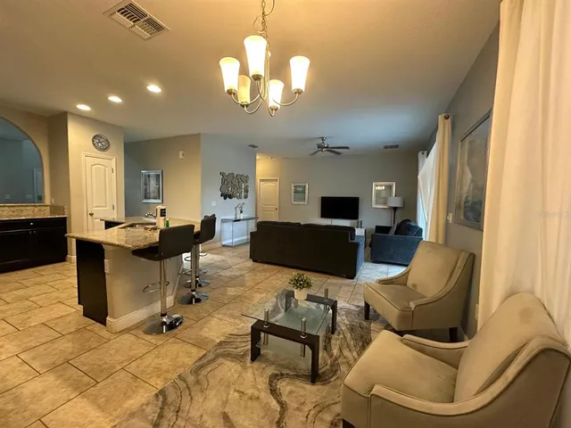 a living room with furniture a dining table and a chandelier