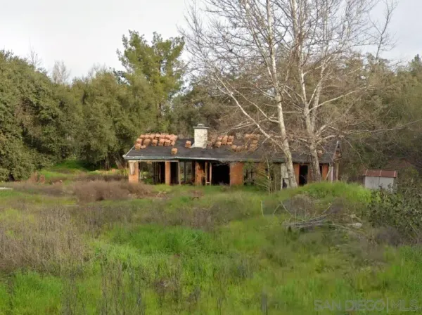 a view of a big house with a big yard and large trees