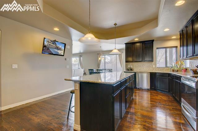 2405 Reed Grass Way Colorado Springs, CO 80915 - Photo 5 of 35 Easily cook and entertain in this space - gleaming hardwood floors and stainless steel appliances (note: range pictured above will not stay with the home). Mounted TV stays. :)