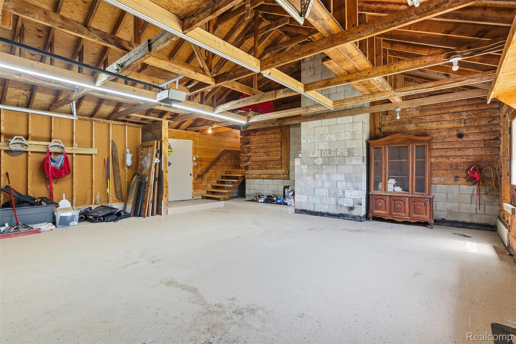 3656 Stanley Road Columbiaville, MI 48421 - Photo 37 of 65 Spacious garage featuring a light-colored concrete floor, exposed wood ceiling beams, and integrated strip lighting