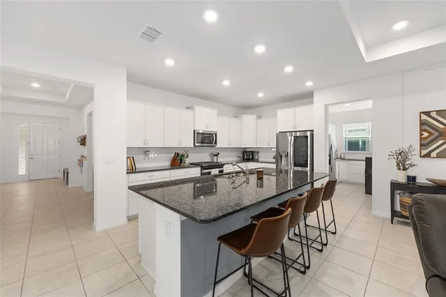 a kitchen with stainless steel appliances granite countertop a table chairs refrigerator and sink